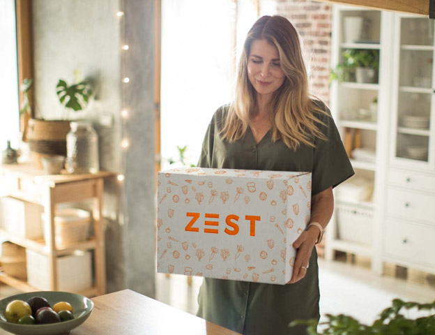 woman holding Zest Cayman meal kit for cooking at home